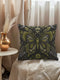 A square decorative pillow featuring an intricately detailed butterfly design in olive green, sage, and cream colors against a black background. The butterfly is surrounded by botanical elements with symmetrical floral patterns.